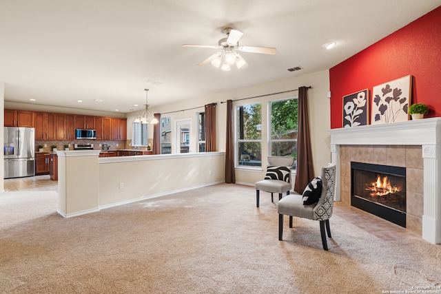 kitchen featuring appliances with stainless steel finishes, hanging light fixtures, ceiling fan with notable chandelier, a fireplace, and backsplash