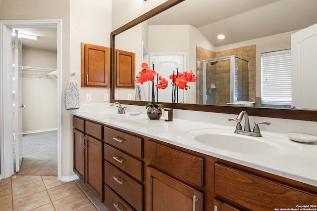 bathroom featuring vanity, a shower with shower door, vaulted ceiling, and tile patterned floors