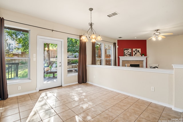 unfurnished dining area featuring ceiling fan with notable chandelier and light tile patterned floors