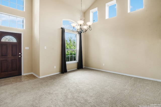 entrance foyer featuring carpet floors, a chandelier, and high vaulted ceiling