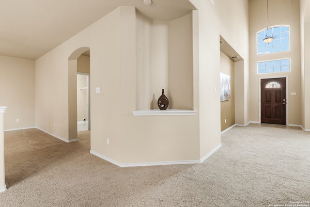 carpeted entrance foyer featuring an inviting chandelier and a towering ceiling