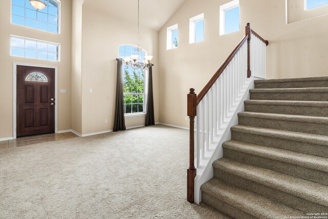 foyer entrance with carpet flooring, a chandelier, and high vaulted ceiling