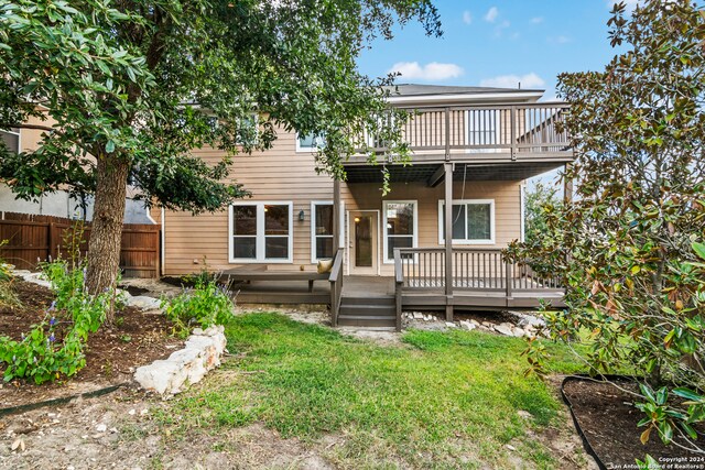 rear view of house featuring a wooden deck and a lawn