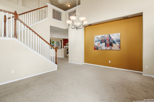 unfurnished room with carpet floors, a notable chandelier, and a towering ceiling