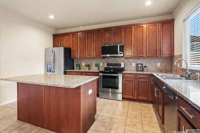 kitchen with light stone countertops, appliances with stainless steel finishes, sink, and a center island