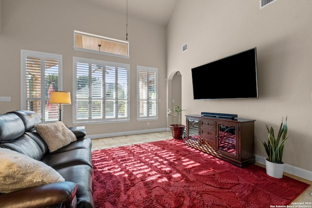 tiled living room with high vaulted ceiling and a healthy amount of sunlight