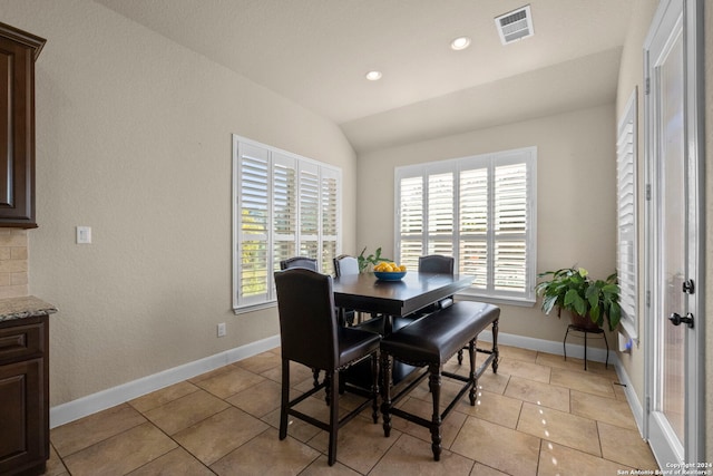 dining area featuring vaulted ceiling and light tile patterned floors