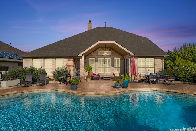 pool at dusk featuring outdoor lounge area and a patio area