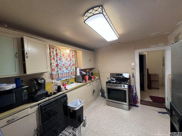 kitchen featuring a textured ceiling, stainless steel range with gas cooktop, and sink