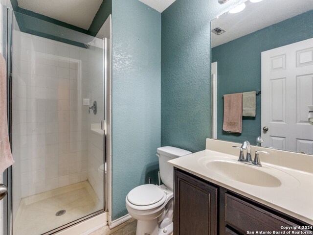 bathroom with toilet, vanity, and a shower with shower door