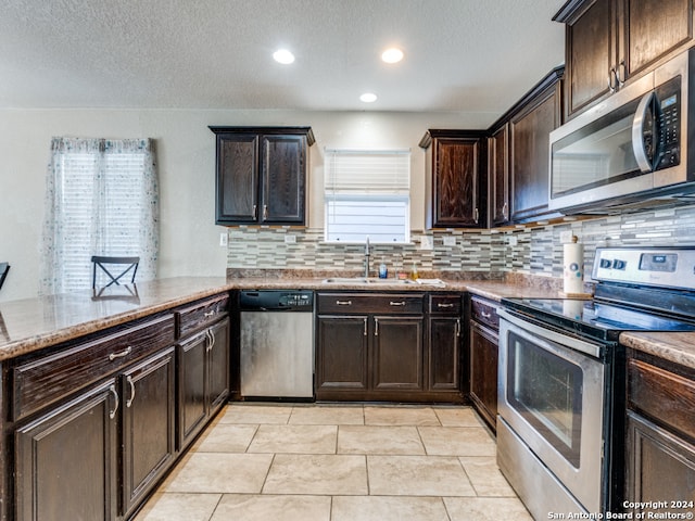 kitchen with sink, stainless steel appliances, decorative backsplash, and kitchen peninsula