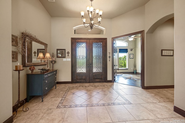 foyer with a textured ceiling, ceiling fan with notable chandelier, light tile patterned floors, and french doors