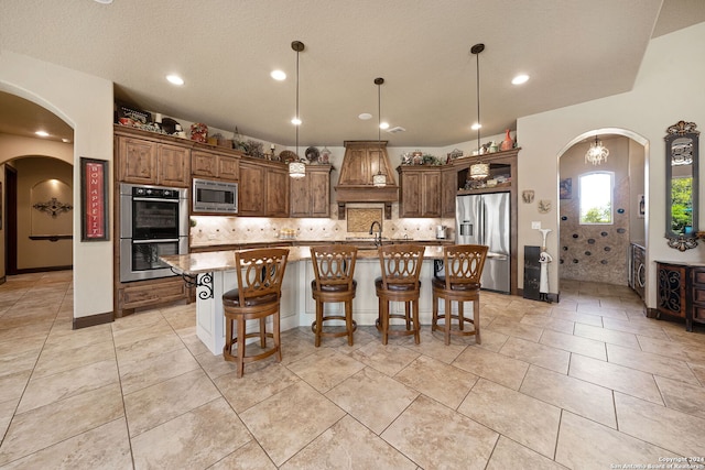 kitchen featuring light stone countertops, pendant lighting, stainless steel appliances, a kitchen bar, and a spacious island