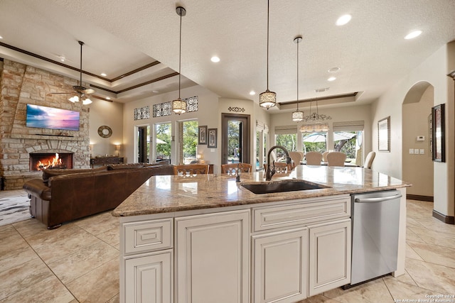 kitchen with ceiling fan, sink, a kitchen island with sink, a fireplace, and a wealth of natural light