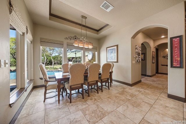 dining area featuring a textured ceiling, crown molding, and a raised ceiling