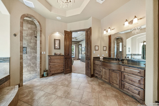 bathroom with an inviting chandelier, a tray ceiling, a shower, and vanity