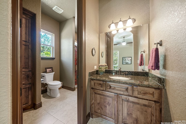 bathroom featuring ceiling fan, vanity, toilet, a textured ceiling, and tile patterned flooring