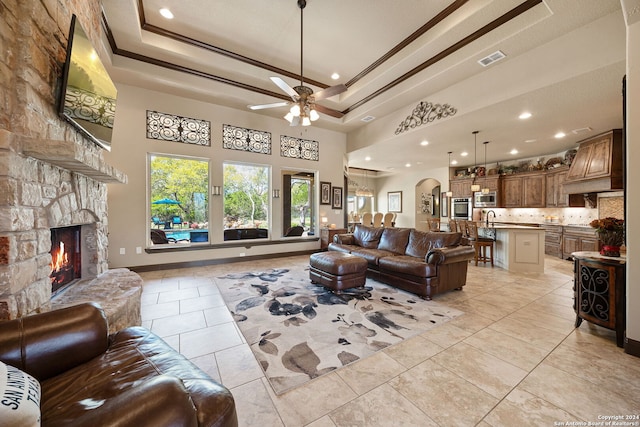 living room with ceiling fan, light tile patterned floors, a fireplace, and a tray ceiling