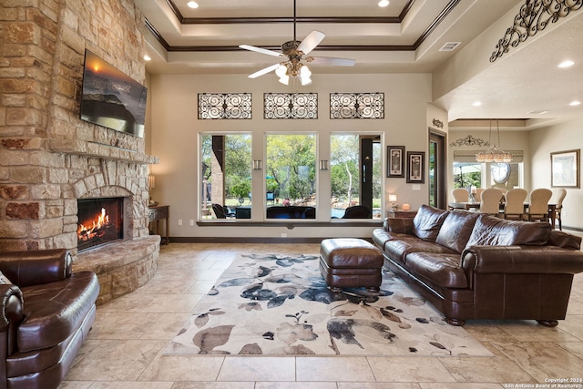 living room with crown molding, a stone fireplace, ceiling fan, and a wealth of natural light