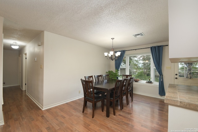 dining room with an inviting chandelier, dark wood-type flooring, and a textured ceiling