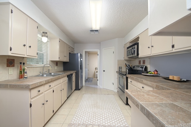 kitchen featuring stainless steel appliances, sink, light tile patterned floors, and decorative backsplash