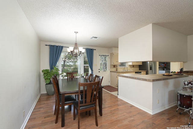 dining space featuring hardwood / wood-style floors, a textured ceiling, and a notable chandelier