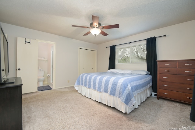 bedroom featuring ensuite bath, light colored carpet, a textured ceiling, a closet, and ceiling fan