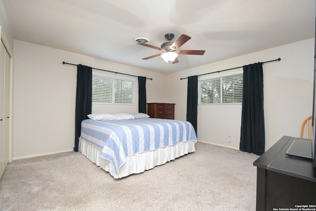 carpeted bedroom with multiple windows, ceiling fan, and a textured ceiling