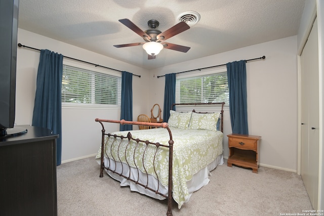 bedroom with light colored carpet, a closet, and a textured ceiling