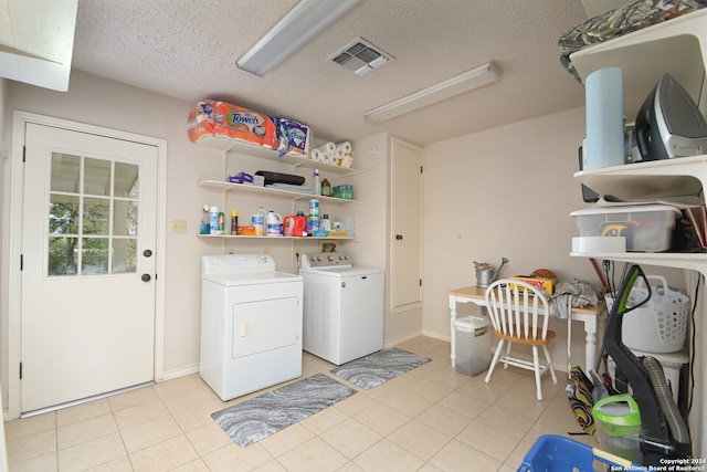 laundry room with washing machine and clothes dryer, a textured ceiling, and light tile patterned floors