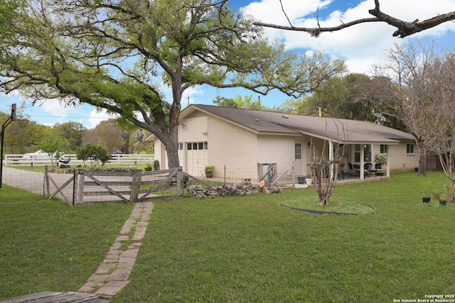 rear view of property with a garage and a lawn