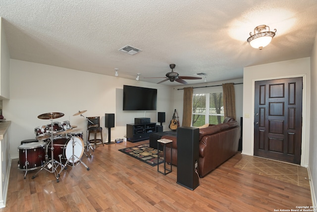 living room featuring ceiling fan, wood-type flooring, and a textured ceiling