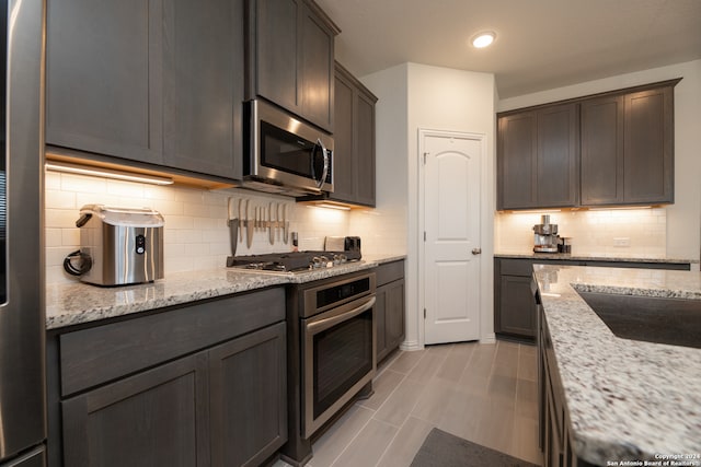 kitchen featuring appliances with stainless steel finishes, light stone counters, and tasteful backsplash