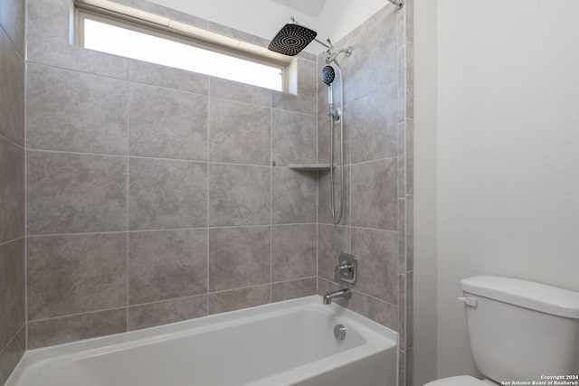 bathroom featuring tiled shower / bath, toilet, and plenty of natural light