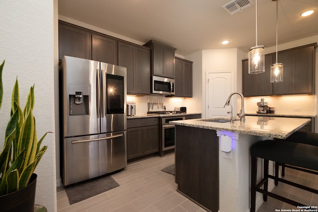 kitchen with appliances with stainless steel finishes, backsplash, sink, and decorative light fixtures