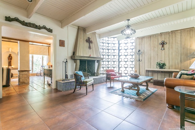 living room with dark tile patterned floors, beamed ceiling, a fireplace, wooden walls, and wooden ceiling