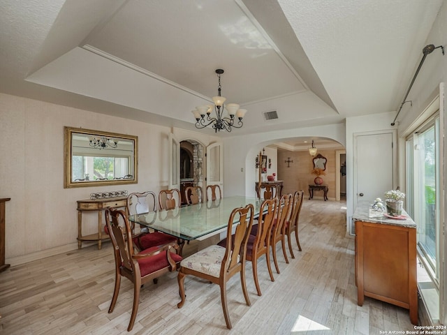 dining room with a tray ceiling, light hardwood / wood-style flooring, and a chandelier