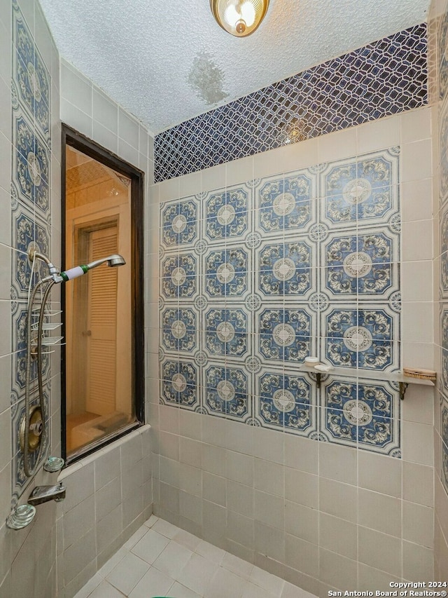 bathroom featuring a tile shower, tile walls, a textured ceiling, and tile patterned floors