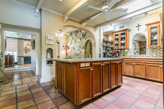 kitchen with ceiling fan, sink, beam ceiling, a center island, and wooden ceiling