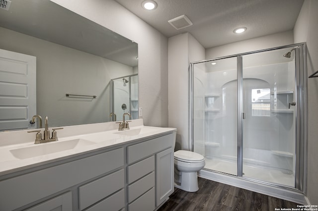 bathroom featuring toilet, wood-type flooring, vanity, a textured ceiling, and an enclosed shower