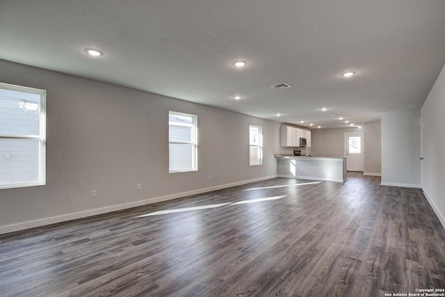 2544 Solon Ln, Seguin, TX 78155 - unfurnished living room featuring baseboards, a healthy amount of sunlight, dark wood-type flooring, and recessed lighting