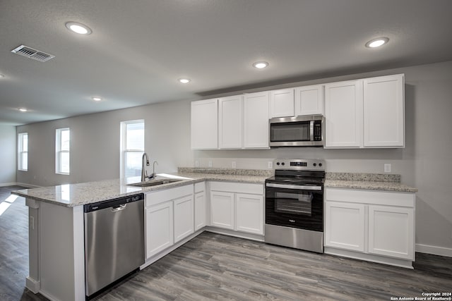 kitchen with dark hardwood / wood-style floors, kitchen peninsula, stainless steel appliances, sink, and white cabinets