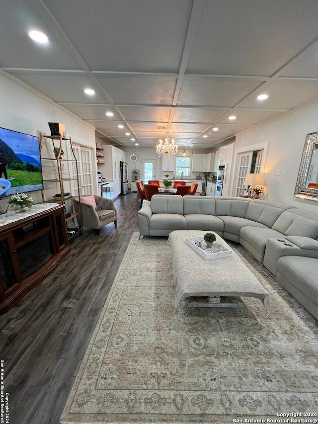 living room featuring coffered ceiling, an inviting chandelier, and dark hardwood / wood-style flooring