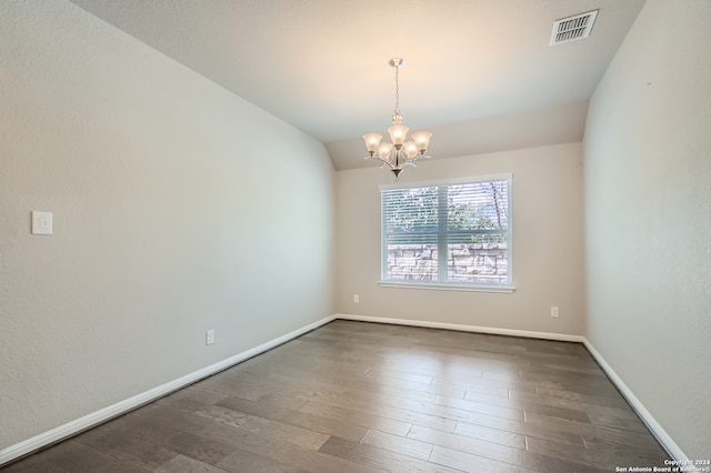 spare room with vaulted ceiling, a notable chandelier, and dark hardwood / wood-style flooring