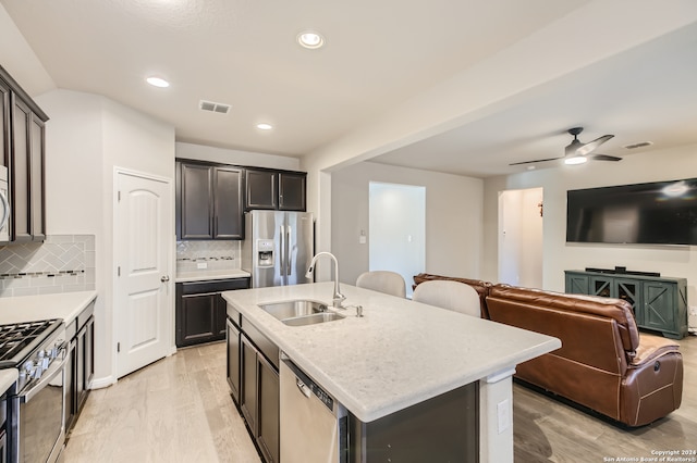 kitchen with light hardwood / wood-style floors, sink, an island with sink, stainless steel appliances, and ceiling fan