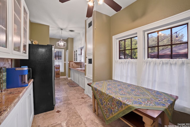 kitchen featuring white cabinets, decorative light fixtures, and light stone counters