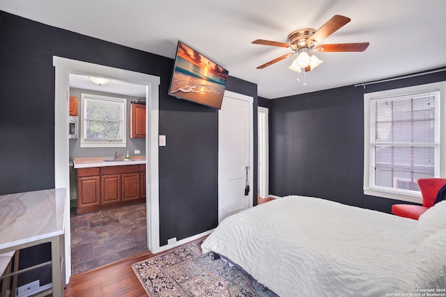 bedroom featuring ensuite bath, ceiling fan, sink, and dark wood-type flooring