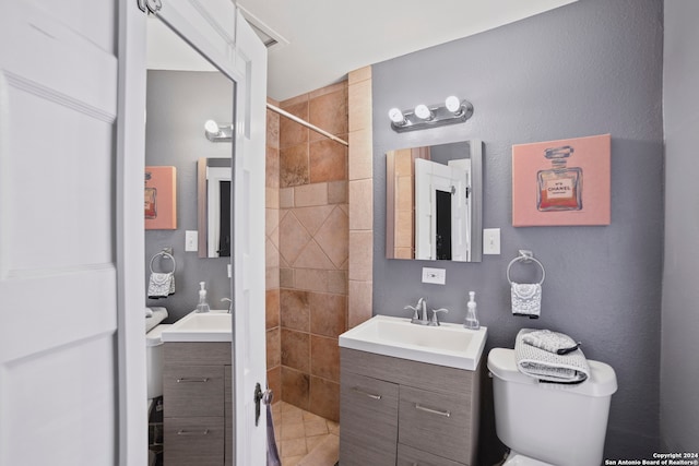 bathroom featuring a tile shower, vanity, and toilet