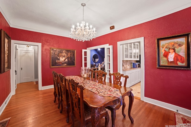 dining space featuring crown molding, light hardwood / wood-style flooring, and a chandelier