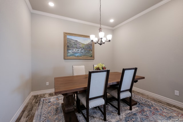 dining area with wood-type flooring, crown molding, and a notable chandelier